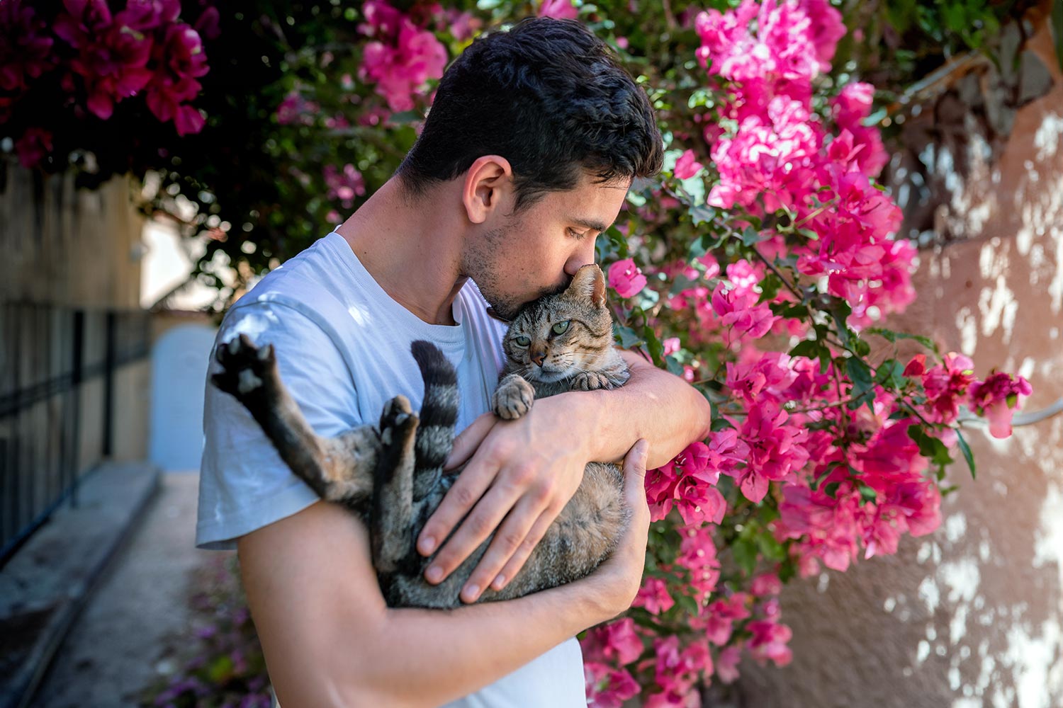 young hispanic man kissing his cat